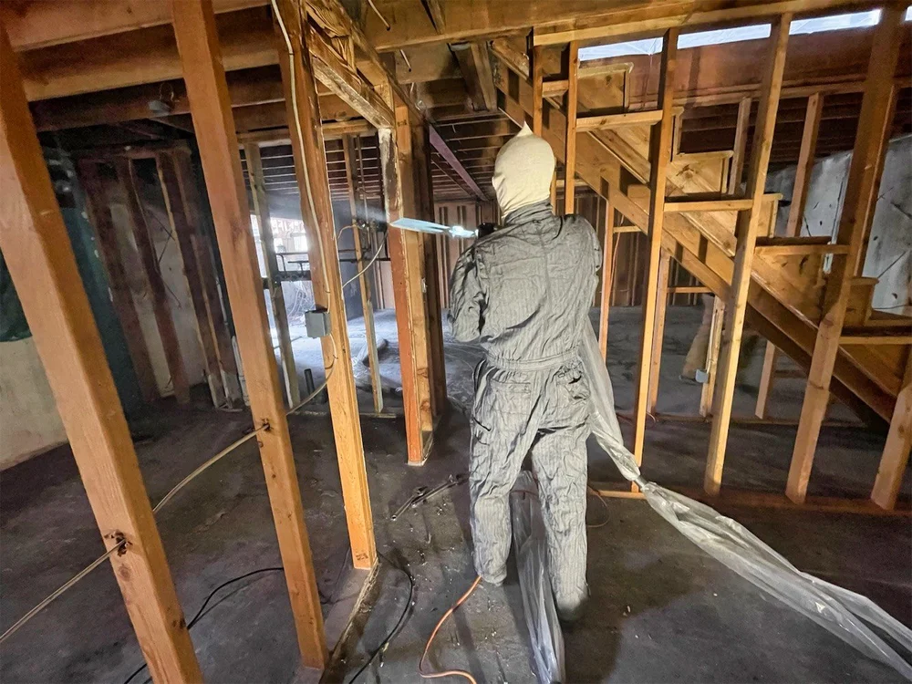 Technician performing dry ice blasting inside wall framing