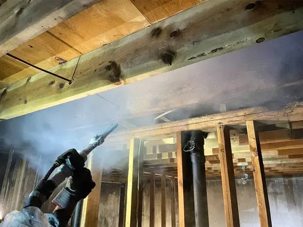 Technician dry ice blasting soot from basement framing